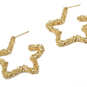 Puede incluir: Un par de pendientes de aro de estrella dorada. Los pendientes están hechos de pequeñas cuentas texturizadas que les dan un aspecto único.