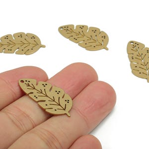 Op de afbeelding: Vier goudkleurige metalen bladbedels met ingewikkelde ader- en stipdetails. Elke bedel heeft een klein gaatje om te rijgen. Deze decoratieve bedels zijn ideaal voor het maken van sieraden of knutselprojecten.