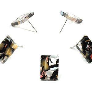 May include: Four pairs of rectangular earrings with a black, white, and brown abstract pattern. The earrings are made of resin and have silver posts.