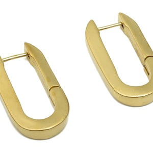 Puede incluir: Un par de pendientes de aro de oro con forma ligeramente ovalada.