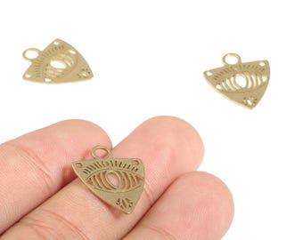 Peut inclure: Pendentifs en forme de triangle en métal doré, avec un motif d'œil et des détails découpés complexes. Les pendentifs ont une petite boucle en haut pour les attacher à des bijoux. Trois pendentifs sont visibles, dont un tenu dans une main.