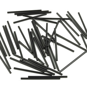 Puede incluir: Un montón de pajitas para beber de plástico negro, esparcidas sobre un fondo blanco.