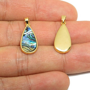 May include: Two gold-colored teardrop pendants. One features a vibrant abalone shell inlay with blue, green, and gold hues. The other pendant is solid gold. Both have a small loop at the top for a chain.