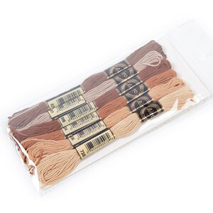 May include: A package of six spools of embroidery floss in shades of brown, beige, and tan. The spools are labeled with the brand name "A&iuml;da" and a barcode.