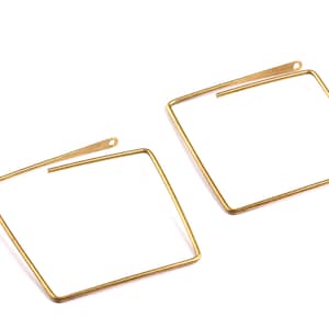 May include: A pair of gold square hoop earrings. The earrings are made of a thin wire and have a simple, modern design.