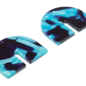 May include: Two U-shaped acrylic pendants. The pendants feature a marbled pattern of blue, purple, and white. Each pendant has a small hole at the top for stringing. The edges are smooth and polished.