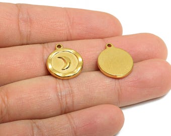 May include: Two gold-colored metal charms. One charm features a crescent moon design within a circular frame. The other charm is a plain, solid circle. Both have a small loop at the top for attaching to jewelry.