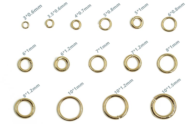 Op de afbeelding: Assortiment van gouden springringen in verschillende maten, vari&euml;rend van 3 mm tot 10 mm in diameter. Elke ring is gelabeld met zijn diameter en dikte in millimeters.