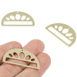 Puede incluir: Encantos de metal dorados en forma de semicírculo con un diseño calado decorativo. Cada dije presenta una fila de recortes ovalados y una abertura rectangular. Los dijes se muestran en una vista de cerca.