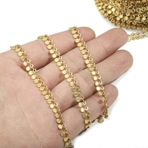 May include: Gold chain trim with small, round, textured metal accents. The chain is shown in three strands on a hand.