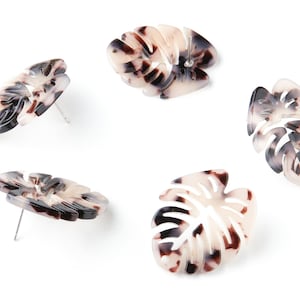 May include: Four pairs of white and brown patterned leaf-shaped earrings. The earrings are made of a lightweight material and have a simple post design.