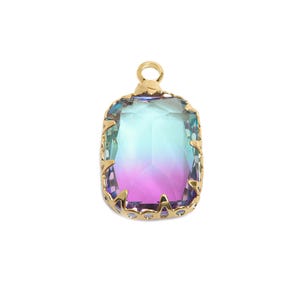 May include: A rectangular pendant with a gold-colored setting and a large, multi-colored gemstone. The gemstone transitions from purple to teal and blue. The gold setting has a decorative, scalloped edge and a small loop at the top for a chain.