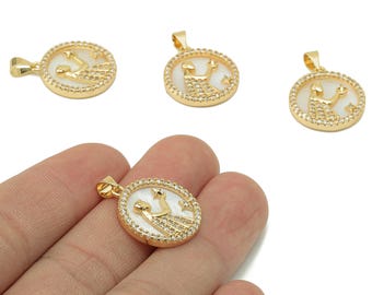 May include: Gold-colored pendant necklaces with a round, white center featuring a design and a border of small, clear stones. The pendants have a loop at the top for a chain. One pendant is held in a hand.