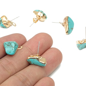 May include: A collection of turquoise and gold-colored stud earrings. The earrings feature irregular, natural-looking turquoise stones with gold-plated edges. The image shows several pairs of earrings, showcasing their design and details.