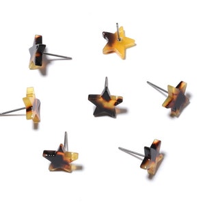 Puede incluir: Seis pares de pendientes en forma de estrella con un patrón de carey y amarillo. Los pendientes están hechos de plástico y tienen una poste de plata.