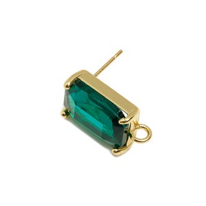 Puede incluir: Un solo pendiente de oro con una gema rectangular de color verde esmeralda. El pendiente tiene un poste para perforar y un pequeño lazo en el extremo. La gema mide aproximadamente 1,3 cm de largo.
