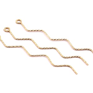 May include: Three gold-colored, twisted wire headpins with a loop at the top. The headpins are wavy and have a pointed end.