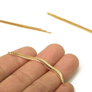 May include: Gold-colored chain connectors with a woven design. The connectors have small loops at each end for attaching to other jewelry components. The image shows the connectors against a white background.