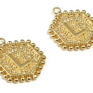May include: Two gold-toned hexagonal charms with a raised letter "L" in the center. Each charm is surrounded by a row of small gold beads.