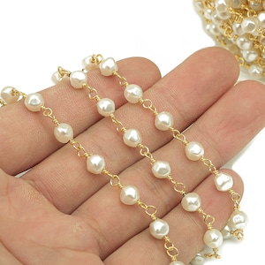 May include: A gold chain with white pearl beads. The chain is made of small, delicate links and the pearls are evenly spaced.