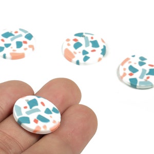 May include: Four round, white ceramic pendants with a terrazzo pattern in shades of teal, pink, and white.