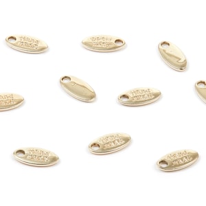 Può includere: Nove etichette ovali in metallo dorato con le parole "Hand Made" incise su di esse.