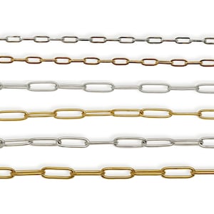 May include: Close-up of several chains in silver and gold tones. The chains have an elongated oval link design. The chains are displayed against a white background. The chains are suitable for jewelry making and crafting.