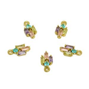 May include: Five gold-toned jewelry charms with colorful rectangular and round gemstones. The gemstones are in shades of blue, purple, pink, and yellow. Each charm has a small loop for attaching to jewelry.