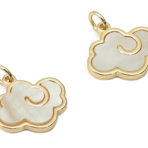 Op de afbeelding: Twee goudkleurige bedels in de vorm van wolken met een witte parelmoer inleg.