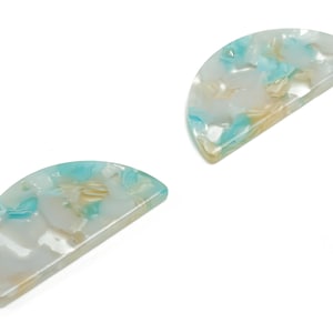 Może przedstawiać: Dwa półkoliste spinki do włosów z marmurowym wzorem w odcieniach bieli, błękitu i beżu.