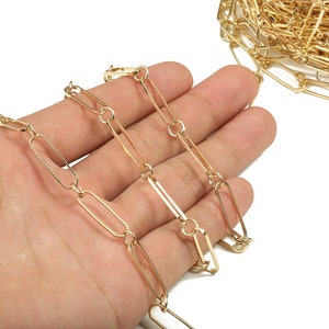 May include: A gold chain with oval links. The chain is lying on a hand.