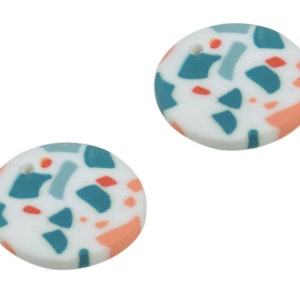 May include: Two round white ceramic pendants with a hole at the top. The pendants have a terrazzo pattern with blue, grey, and peach accents.