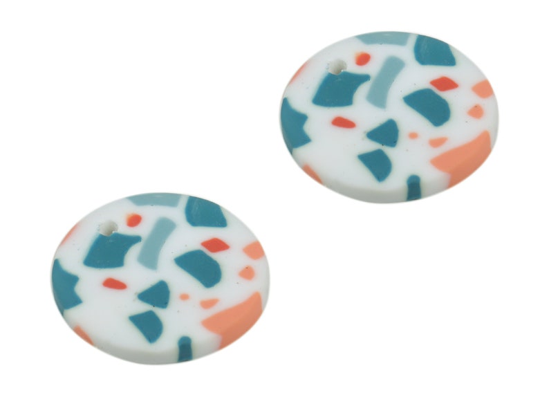 May include: Two round white ceramic pendants with a hole at the top. The pendants have a terrazzo pattern with blue, grey, and peach accents.