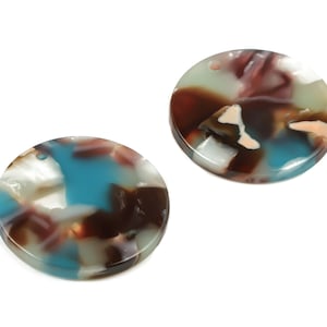 May include: Two round, colorful, resin, decorative pieces with a mottled pattern of brown, blue, white, and pink.
