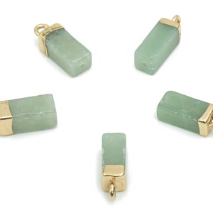 Puede incluir: Cinco colgantes rectangulares de piedra de jade verde con tapas y lazos de metal dorado. Los colgantes miden aproximadamente 2,5 cm de largo.