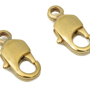 Puede incluir: Dos cierres de langosta de color dorado para la elaboración de joyas. Los cierres son de metal y tienen un acabado brillante.