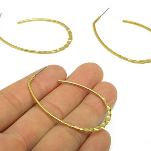 May include: Three gold hoop earrings with a textured finish. The earrings are oval shaped and have a wire hook closure.