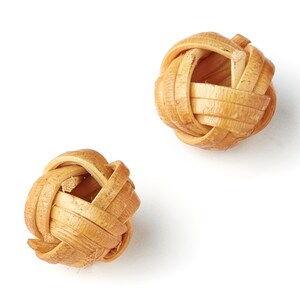 Puede incluir: Dos bolas tejidas de materiales naturales, de color marrón claro. Las bolas son redondas y tienen una superficie texturizada.