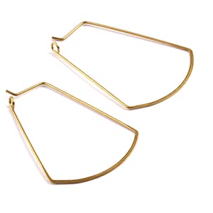 May include: A pair of gold-toned hoop earrings with a slightly curved, geometric shape.