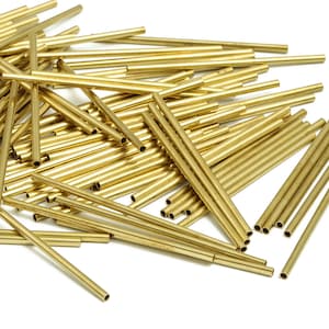 Puede incluir: Un montón de tubos de latón dorado brillante, algunos son más largos que otros, todos son redondos y lisos.