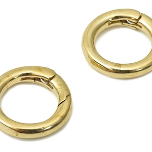 May include: Two gold-coloured metal rings with a hinged opening. The rings are smooth and shiny.