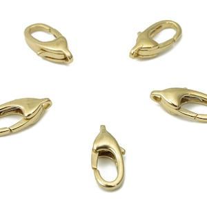 Puede incluir: Cinco cierres de langosta de metal dorado, cada uno con una abertura de resorte y un acabado liso y redondeado.