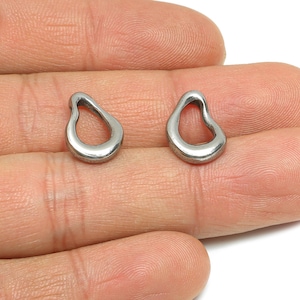 May include: A pair of silver-coloured, open teardrop-shaped earrings. The earrings have a smooth, polished finish. They are small, and are displayed on a person's hand. These earrings are a simple, elegant accessory, suitable for everyday wear.