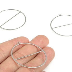 May include: Silver-colored metal earring components. Each component is a circle with a straight bar across the middle. The components have a small loop at the top for attaching to an earring hook. The components are shown against a white background.