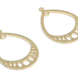 May include: Two gold-tone metal earring blanks with a crescent moon design. The blanks are shaped like teardrops and have a loop at the top for attaching earrings.