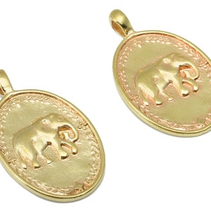 Op de afbeelding: Twee ovale hangers in goudkleur, elk met een olifantmotief. Beide hangers hebben bovenaan een lus om aan een ketting te bevestigen.