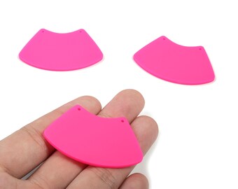 May include: Three bright pink, fan-shaped earring components with two small holes at the top for attachment. One is held in a hand. The components have a smooth, flat surface and a curved bottom edge.