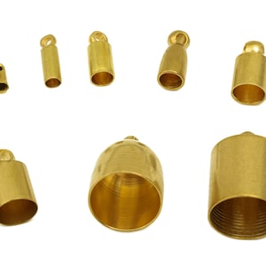 May include: Assortment of gold-toned metal end caps for jewellery making. The end caps are in various sizes and styles, including round, cylindrical, and with a loop.