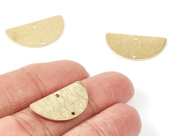 May include: Three brass-coloured, half-moon shaped jewellery findings. Each finding has a textured surface and two small holes for attaching to other components. One finding is held in a hand.