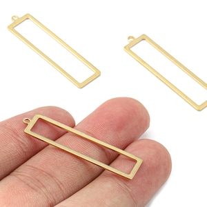 May include: Gold-coloured rectangular pendant charms with a loop at the top for jewellery making. The charms are shown in a hand, with two additional charms visible in the background. These charms are ideal for creating necklaces, earrings, and bracelets.
